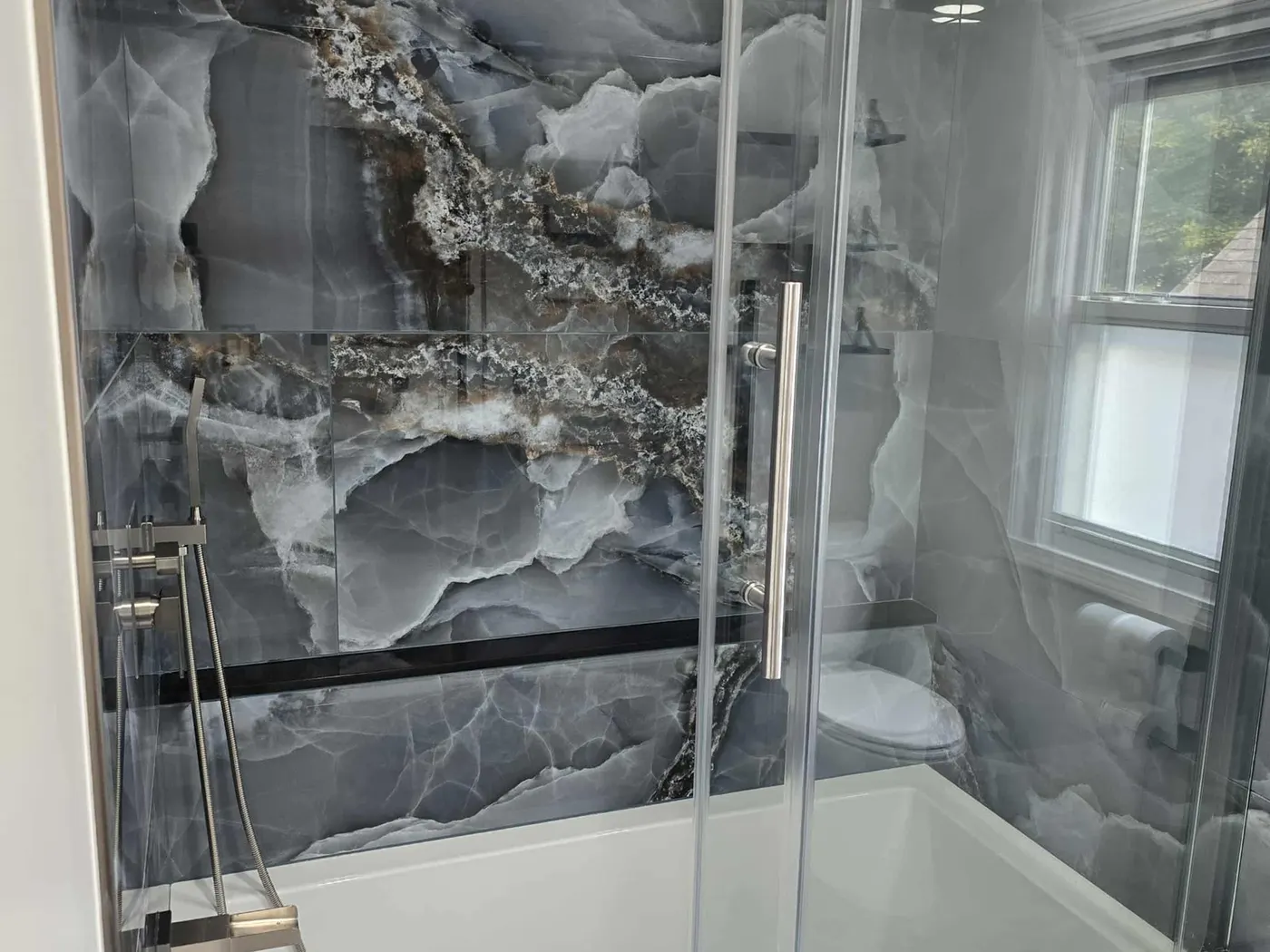 Dark stone-look tub surround with frameless glass