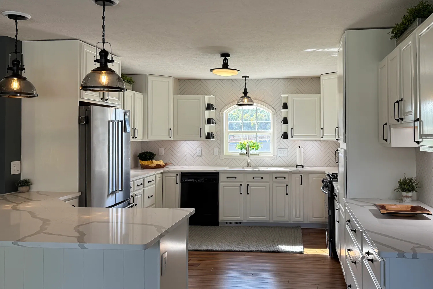 After: the same sink wall with white painted cabinets, black pulls and white herringbone tile