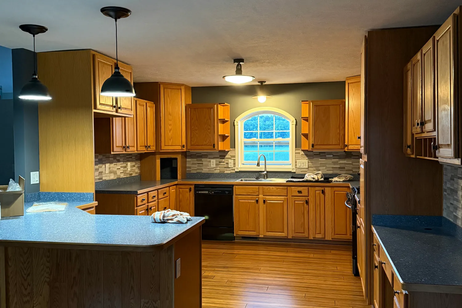 Before: the sink wall with oak cabinets and a gray mosaic tile backsplash