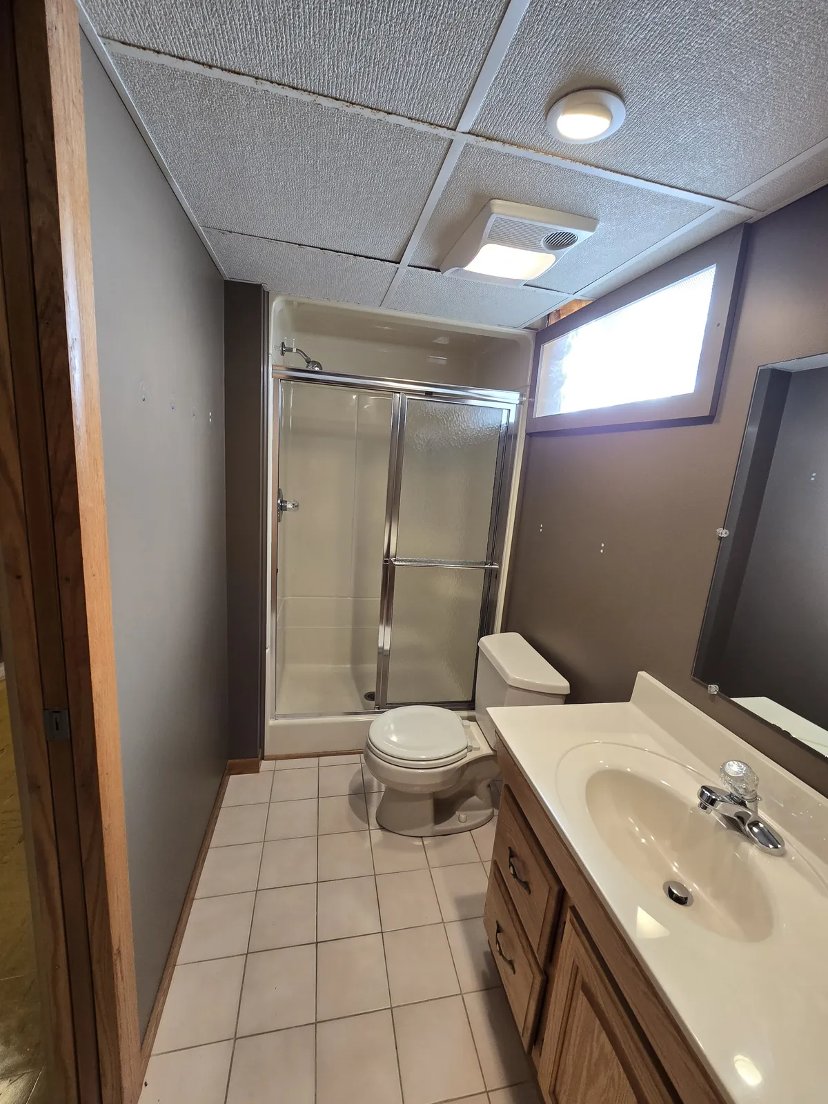 Before: cramped basement bath with acoustic tile ceiling