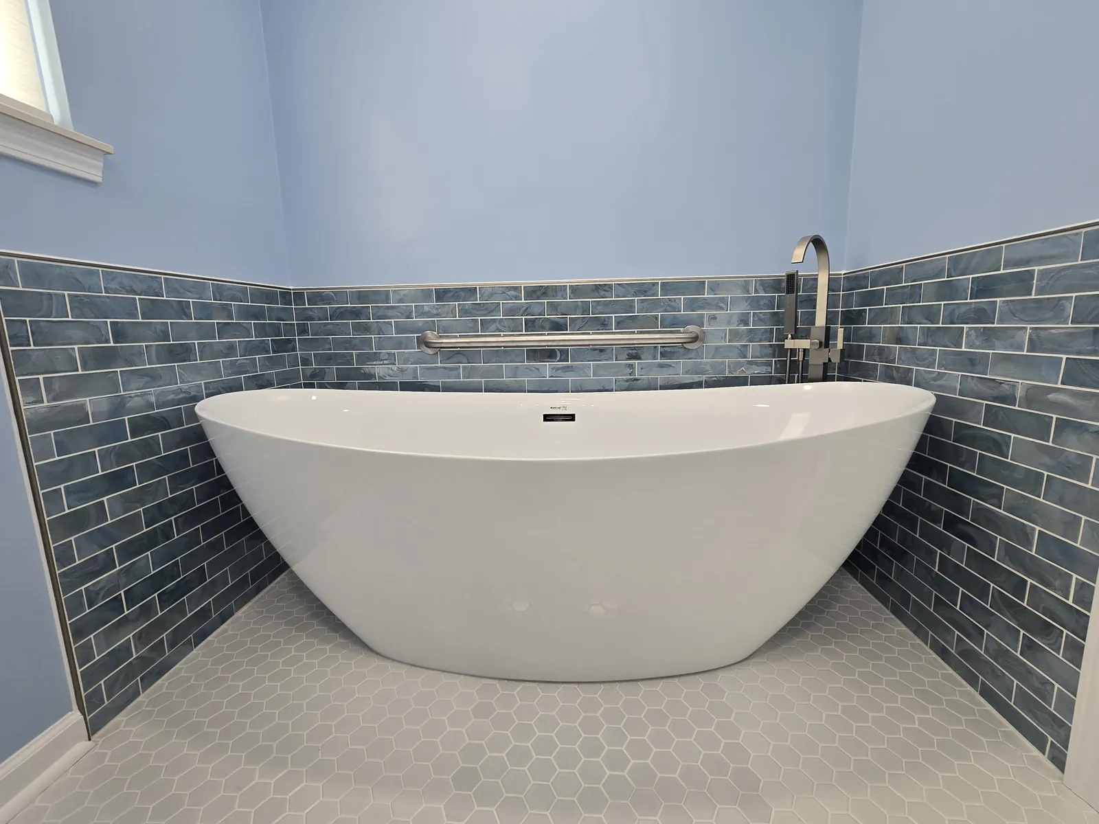 Finished: freestanding tub with blue subway surround and hex tile floor