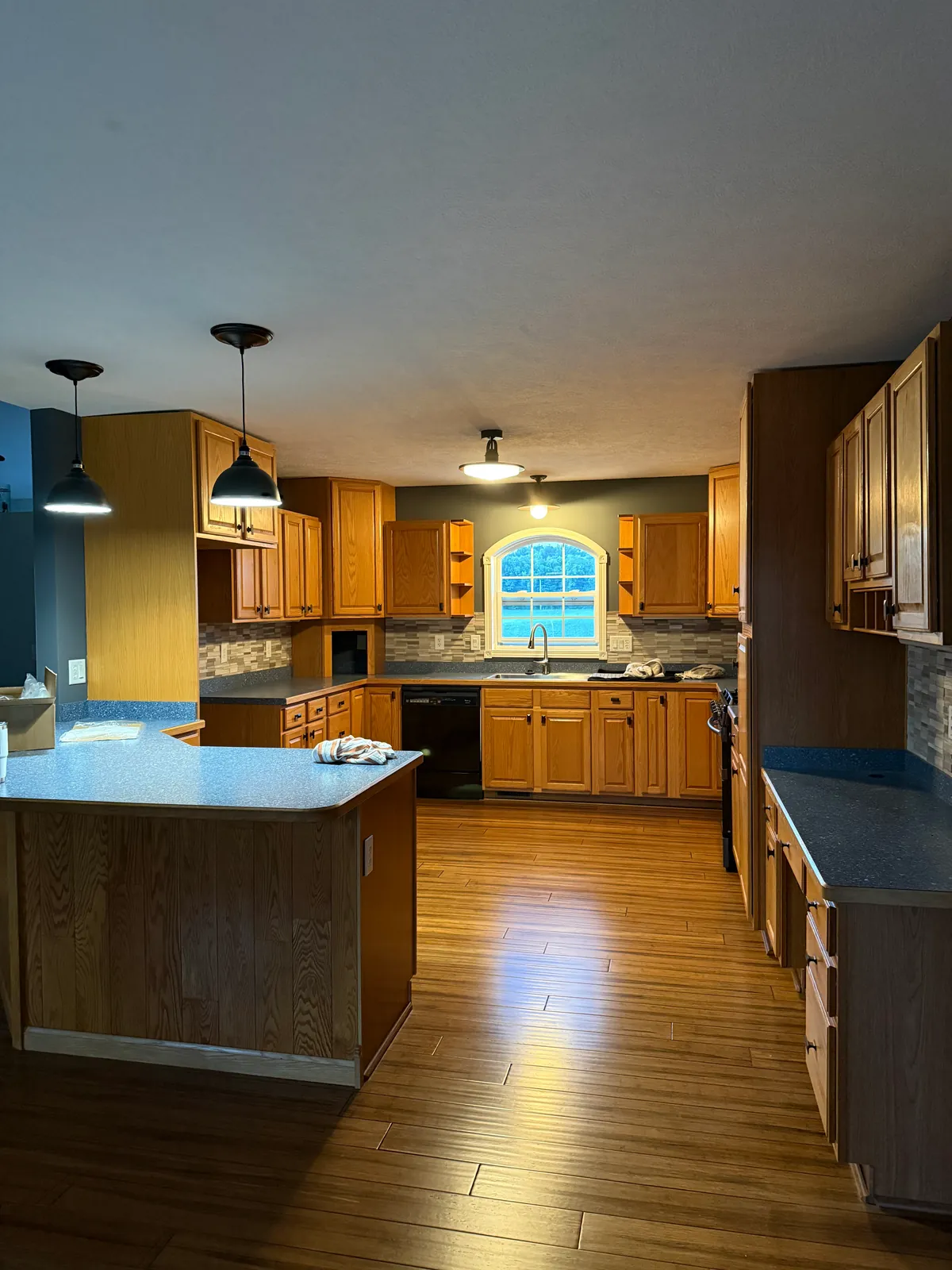 Before: oak cabinets, a gray mosaic tile backsplash and the arched window over the sink