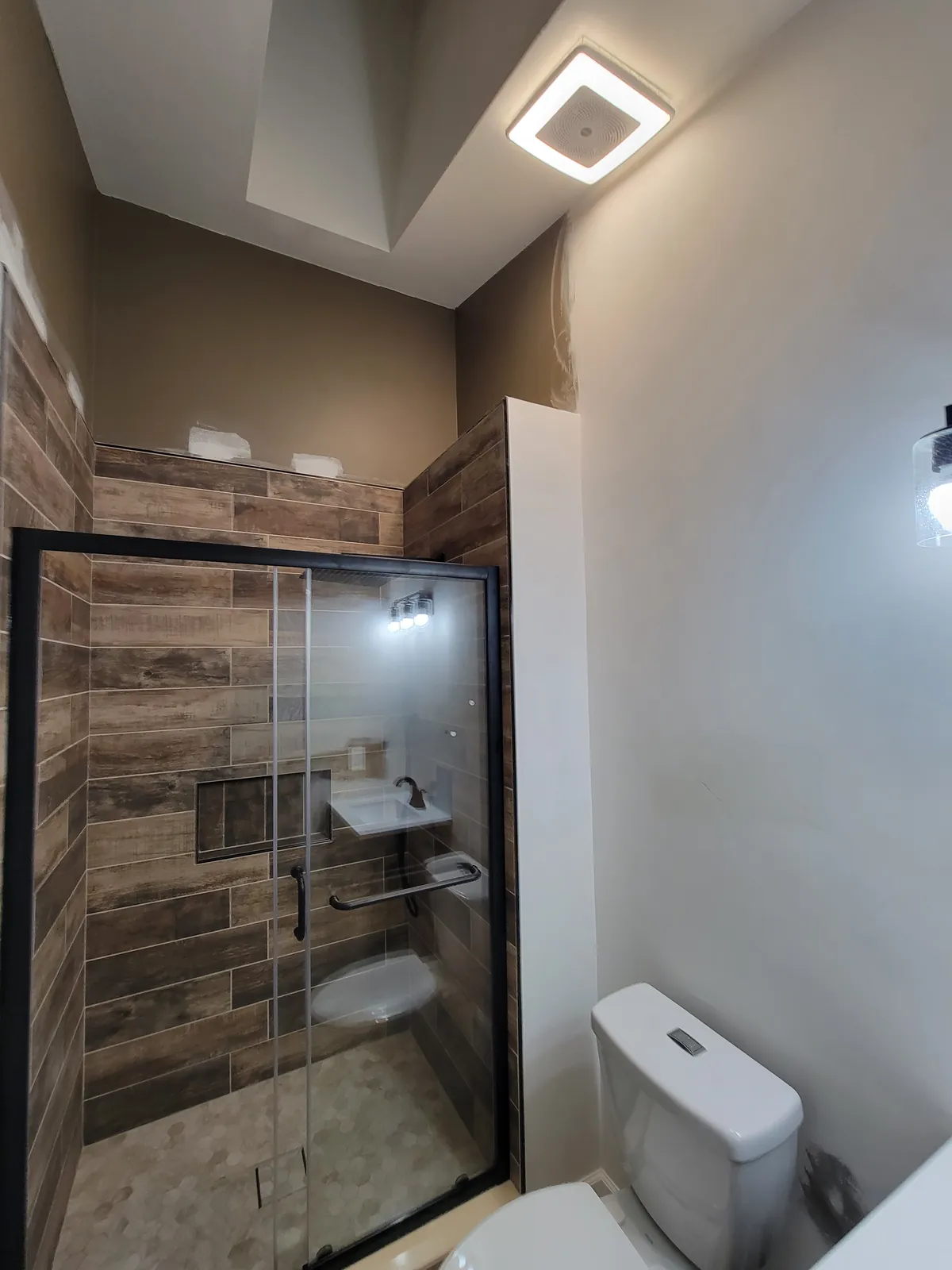 Finished custom shower in Howell: wood-look plank tile and black-framed glass