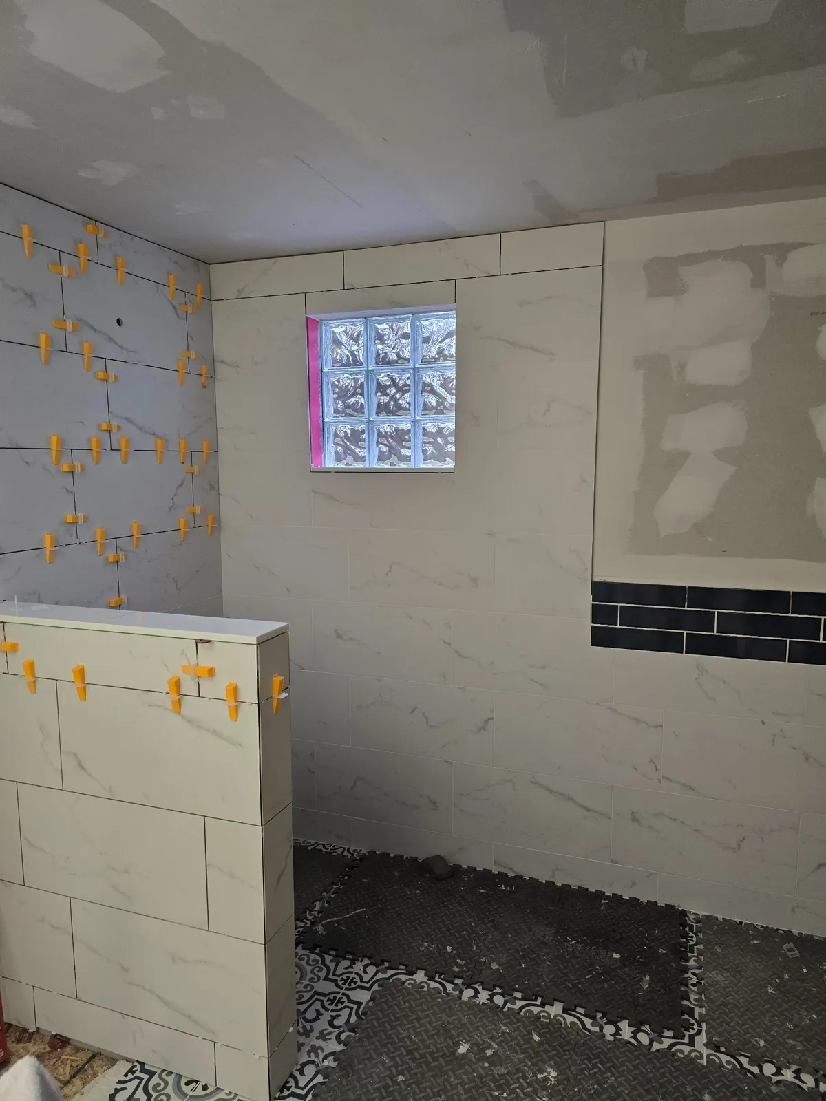 Marble-look tile with a black accent band going up over the new floor