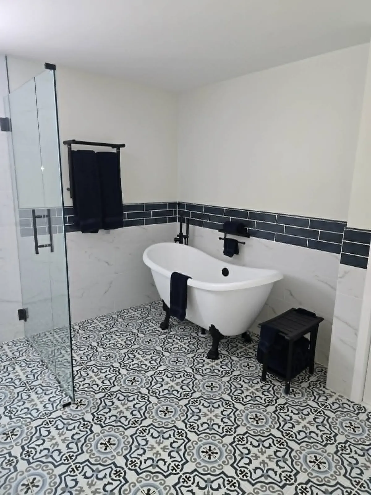 The finished Milford bath: clawfoot tub, glass shower and patterned floor