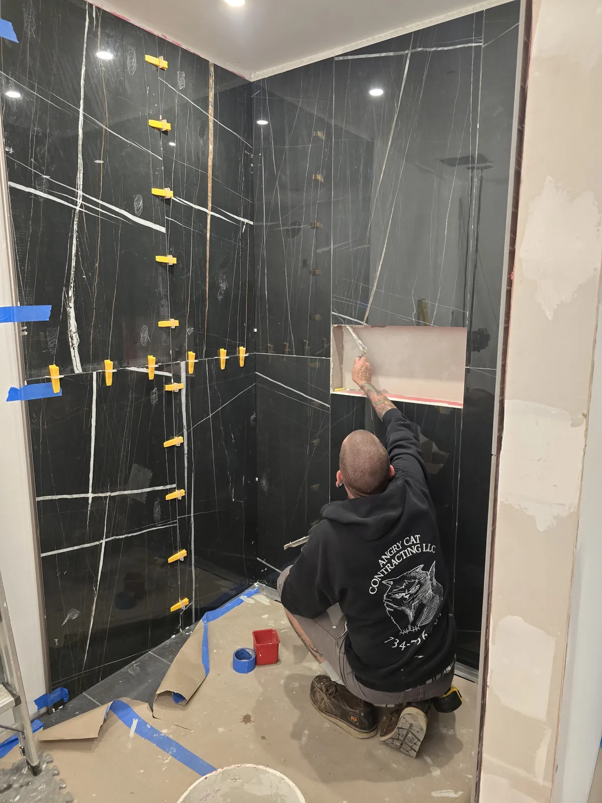 Angry Cat crew setting slab-look black porcelain panels