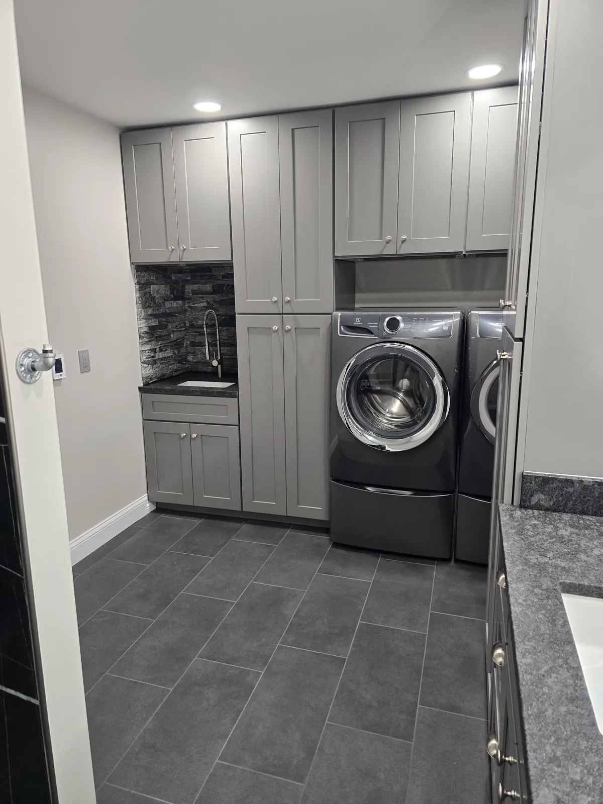 Finished laundry wall: gray shaker cabinets and new tile floor