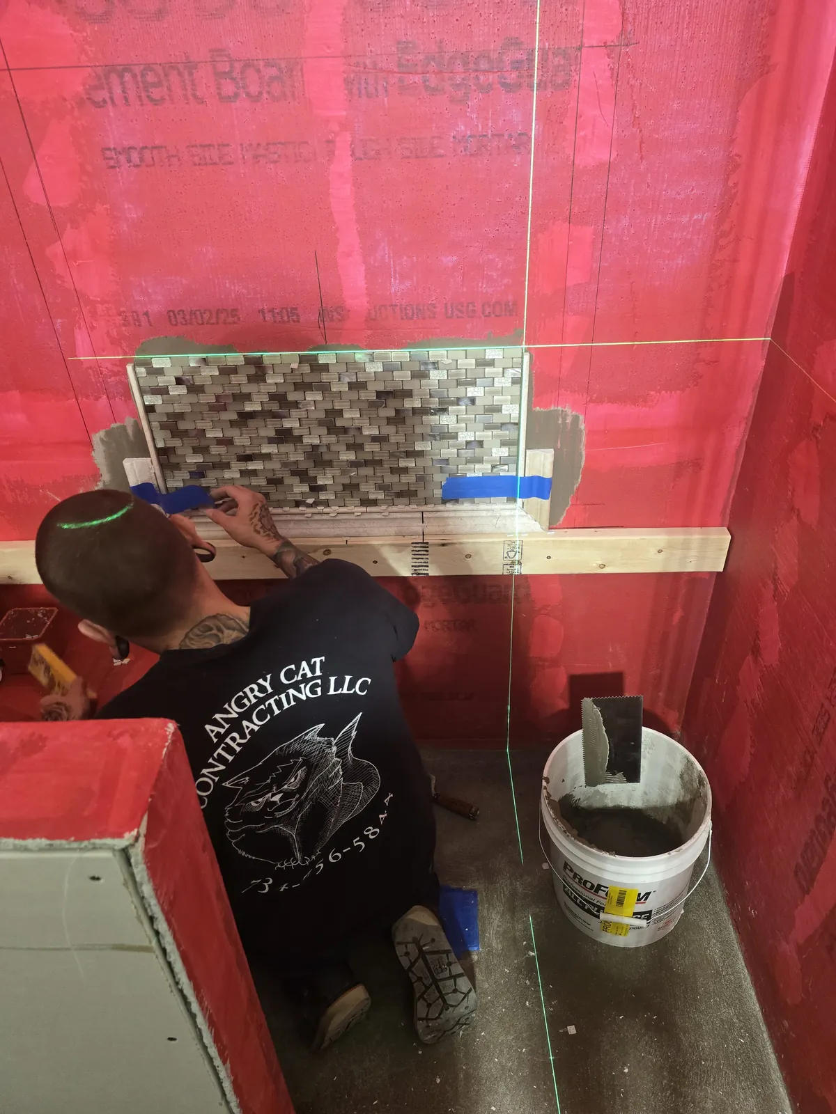 Angry Cat crew setting mosaic accent tile over waterproofing membrane