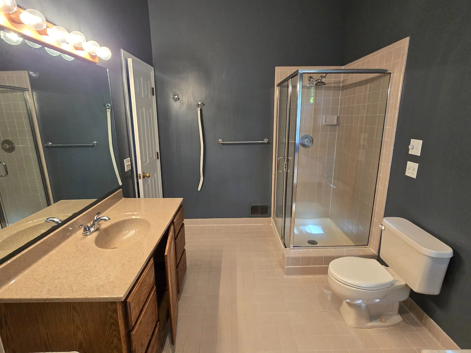 Before: the original primary bath with a small stall shower and dated finishes