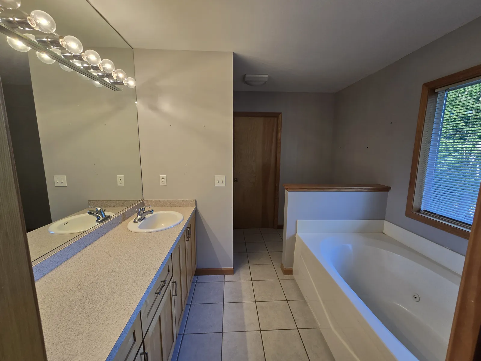 Before the remodel: 1990s Wixom bathroom with an almond double vanity and drop-in tub