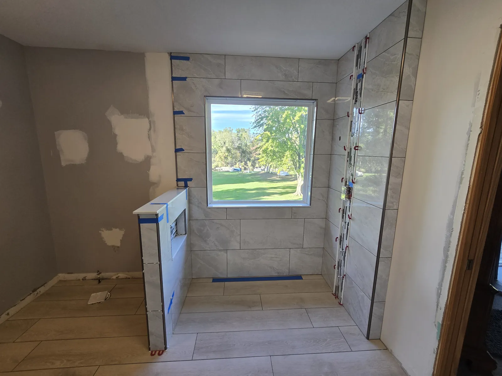 Large-format tile going up around the shower window wall