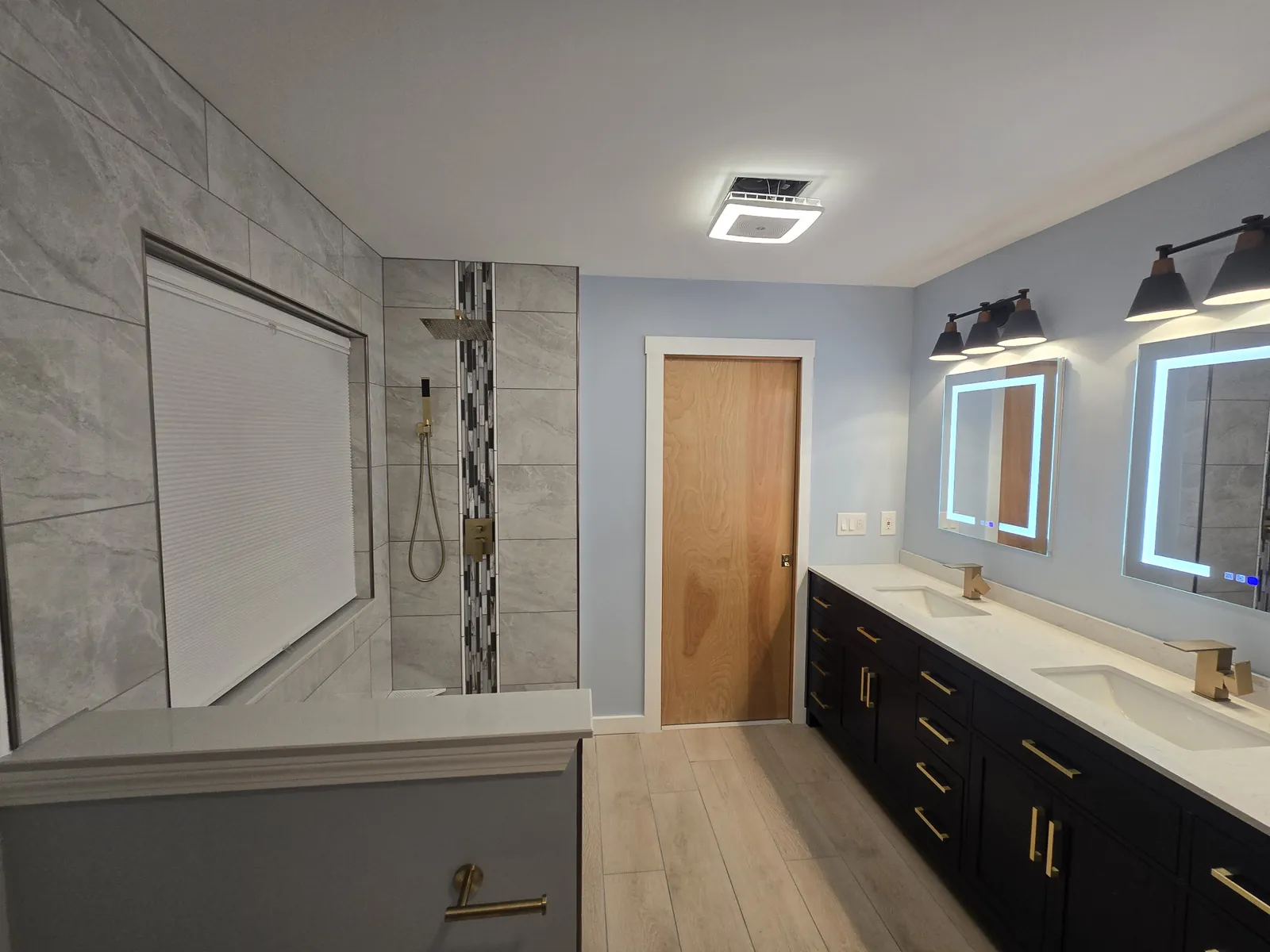 The finished Wixom bathroom: custom tiled shower and navy double vanity with LED mirrors