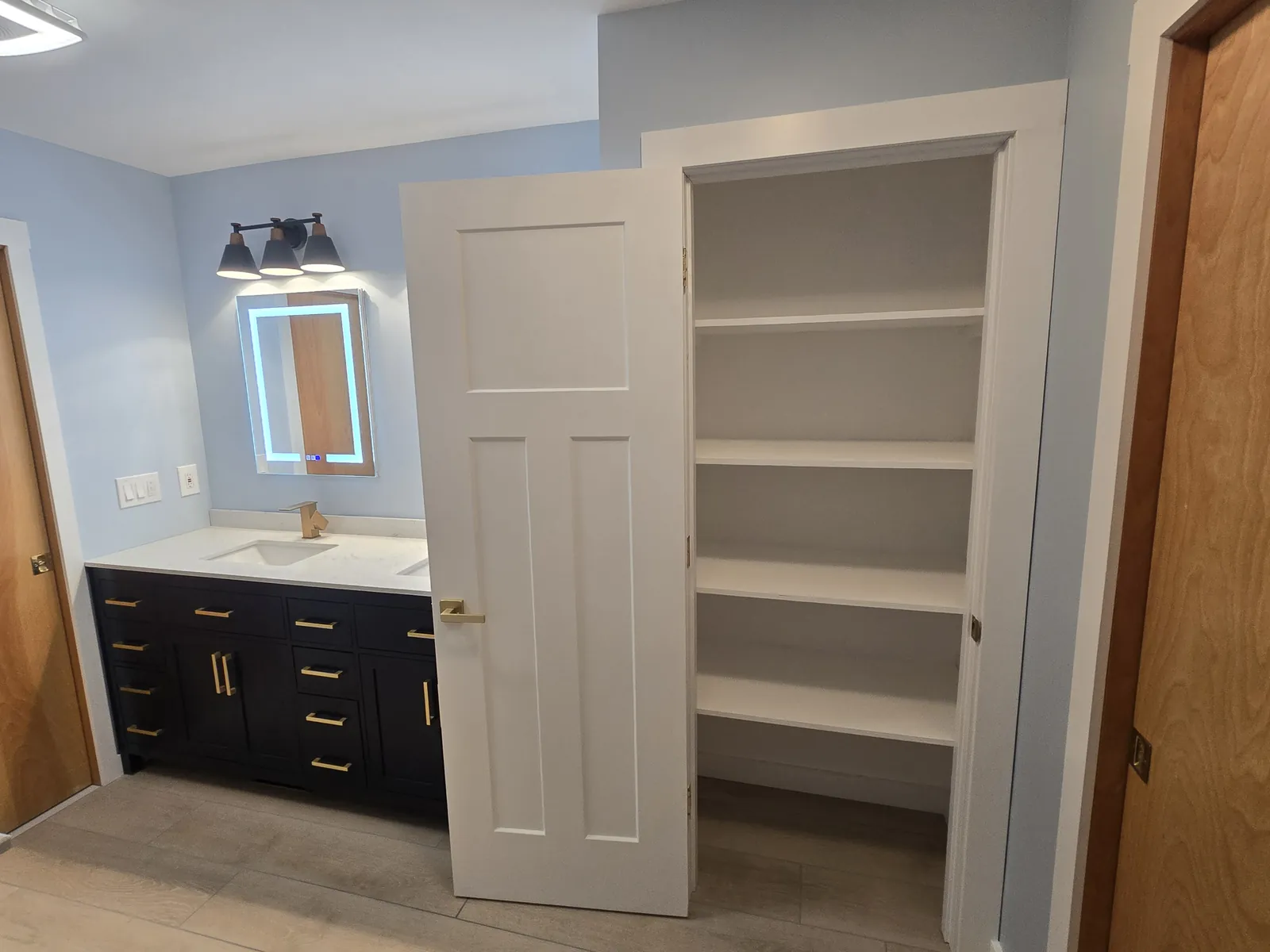 Navy vanity with gold pulls and a new built-in linen closet